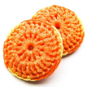 May include: Two round, crocheted items in shades of orange and yellow. The items have a textured, circular pattern, with a central hole. The color gradient transitions from a bright orange center to a yellow edge. The items are set against a white background.