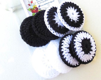 May include: A collection of handmade crochet facial rounds in black and white. The rounds are in various designs, including solid black, solid white, and a black and white starburst pattern. A small card with text and a bee illustration is visible.