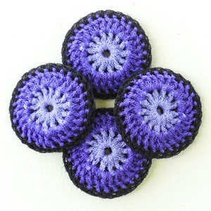 May include: Four handmade crochet coasters. Each coaster features a circular design with a gradient of purple and light blue, framed by a black border. The coasters are arranged in a square formation against a white background.