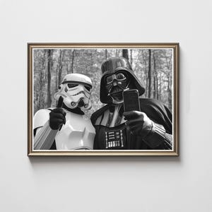 Könnte beinhalten: Schwarz-Weiß-Druck in einem Rahmen, der einen Sturmtruppler und Darth Vader zeigt, die ein Selfie machen. Die Charaktere tragen ihre ikonischen Helme und Rüstungen und halten ein Smartphone. Der Hintergrund ist ein Wald.