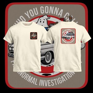Puede incluir: Camisetas de color blanco roto con un diseño gráfico que presenta un fantasma de dibujos animados, un coche blanco y el texto "Who You Gonna Call?" y "Paranormal Investigation Unit". El diseño es en rojo, blanco y negro.