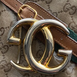 K&ouml;nnte beinhalten: Eine goldene und silberne, ineinandergreifende G-Schnalle mit einem braunen Lederg&uuml;rtel. Die Schnalle ist ein beliebtes Designelement f&uuml;r Luxusmodeaccessoires.
