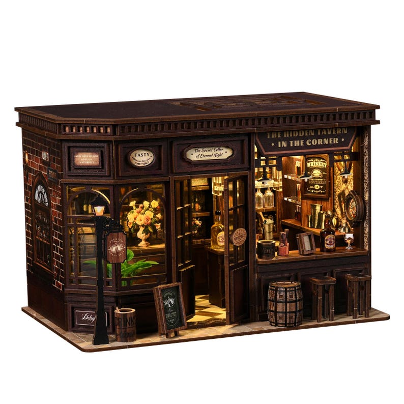 May include: A detailed miniature wooden tavern model, featuring brickwork, windows, and a sign reading "The Hidden Tavern - In The Corner." The interior is illuminated, revealing bottles, glasses, and a bar. A small sign reads "Whiskey."