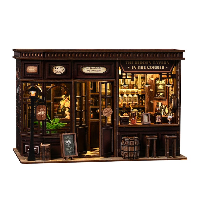 May include: A detailed miniature wooden tavern, labelled "The Hidden Tavern - In The Corner." The facade includes windows, a door, and a street lamp. Inside, a bar is visible, stocked with bottles and glasses, and a small barrel is present.