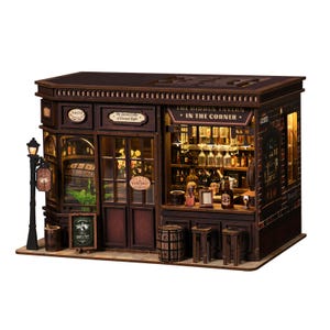 May include: A detailed miniature wooden tavern model. The sign above the entrance reads "The Hidden Tavern - In The Corner." The model includes a street lamp, barrels, and small stools. Interior lighting is visible through the windows, showcasing bottles and glasses.