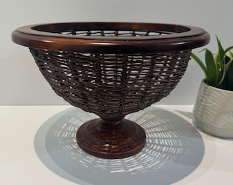 Cesta de frutas vintage tejida sobre una estructura metálica con pedestal de madera.