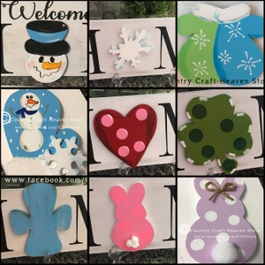 May include: A set of nine wooden home decor signs with various seasonal themes. The signs feature a snowman, snowflake, heart, shamrock, cross, bunny, and mitten. Each sign is painted in bright colors and has a unique design.