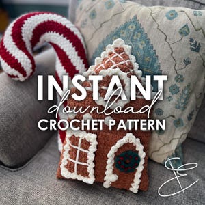 May include: Crochet pattern for a gingerbread house cushion. The cushion is brown with white icing and a green wreath. The text "INSTANT download CROCHET PATTERN" is on the image.