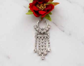 May include: A silver nose ring with a dangling chain of rhinestones. The chain is made up of multiple rows of small rhinestones, and the ring itself is decorated with a cluster of rhinestones.