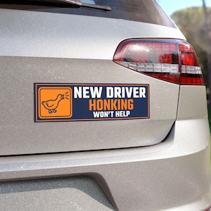 Op de afbeelding: Een rechthoekige bumpersticker met een donkerblauwe achtergrond en een oranje vierkant aan de linkerkant met een witte lijntekening van een gans. De tekst NEW DRIVER HONKING WON'T HELP staat in witte en oranje hoofdletters aan de rechterkant.