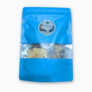 May include: A bright blue resealable pouch containing a dried botanical mix. A circular label on the front features the text Samhain by the Sea, with illustrations of dried fruit slices, star anise, and berries visible through the clear window.