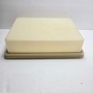 May include: A rectangular, off-white plastic storage container with a smooth, solid lid and a slightly darker beige base. The container features a clean, minimalist design with rounded corners and a flat top surface, providing a simple storage solution.