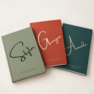 May include: Three hardcover planners in sage green, terracotta, and dark teal. Each features a large script name on the cover: Skylar, Georgia, and Amanda. Below each name, the text reads Monthly Overview Planner in a clean font.