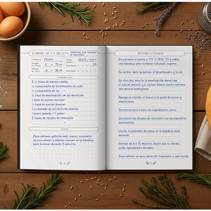 May include: A cookbook open to a recipe for cookies, with ingredients like eggs, flour, and chocolate chips. The image is on a wooden surface with sprigs of rosemary and a loaf of bread.