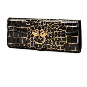 May include: Black clutch with a gold crocodile pattern and a gold swan clasp. The rectangular bag has a glossy finish. The clasp features two swans facing each other, forming a ring.