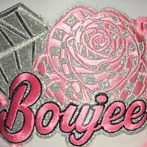 Pode incluir: Patch bordado com a palavra "Boujee" em rosa com contorno preto e detalhes em glitter prateado. O design inclui uma rosa rosa e uma forma de diamante, todos com detalhes brilhantes. Adequado para roupas ou acessórios.