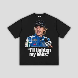 May include: A black short-sleeve t-shirt featuring a graphic print of a race car driver wearing a blue racing suit and a black cap with the text Spectrum. Below the driver, the text reads, "I'll tighten my belts." The shirt has a crew neckline.