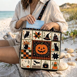 Può includere: Una borsa tote trapuntata con un design patchwork a tema Halloween, che include una zucca centrale, un gatto nero, un gufo, un cappello da strega, un fantasma, un pipistrello e un calderone. La borsa ha una tracolla nera e contiene un libro.