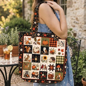 May include: A quilted tote bag featuring a patchwork design of autumn-themed illustrations including a fox, squirrel, rabbit, owl, hedgehog, raccoon, pumpkins, sunflowers, mushrooms, a lantern, and a wagon, framed by a black floral border.
