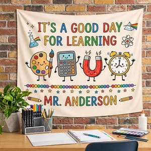 May include: A cream-colored fabric wall hanging featuring the text IT'S A GOOD DAY FOR LEARNING and MR. ANDERSON. The design includes colorful cartoon illustrations of a paint palette, calculator, magnet, alarm clock, and science icons.