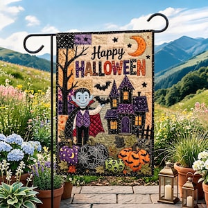 May include: A rectangular quilted garden flag featuring a cartoon vampire, a haunted house, bats, and pumpkins. The text Happy HALLOWEEN is printed in the centre. The design includes purple, orange, black, and cream colours with stitched details.