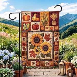 Puede incluir: Una bandera de jardín rectangular con un diseño acolchado que presenta un arreglo central de girasoles y hojas de arce. El borde muestra calabazas, maíz, trigo, bellotas y bayas en tonos otoñales de naranja, amarillo y marrón.