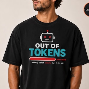 May include: A black short-sleeve t-shirt featuring a white robot head icon with red X eyes, the text OUT OF TOKENS in white and blue, a red loading bar labeled 100% used, and the text Weekly limit resets Sat 7:59 AM printed in white and red.