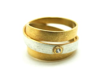 May include: A gold and silver ring with a small diamond set in the center. The ring is made of two bands that are intertwined.