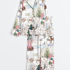 May include: A white long-sleeve pajama set featuring a festive winter scene print with deer, polar bears, Christmas trees, and colorful ornaments. The button-down top has a notched collar with green piping, and the matching pants have a straight leg.