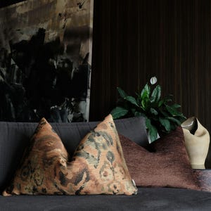 Set of decorative pillows with abstract woven pattern in terracotta, brown and olive tones, styled on a modern sofa