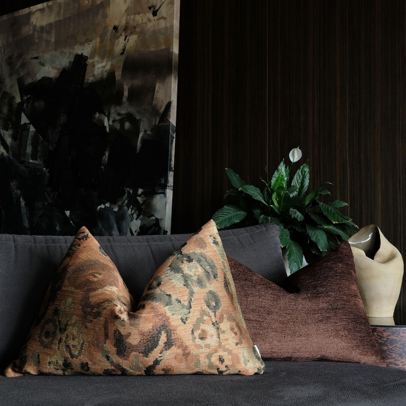 Set of decorative pillows with abstract woven pattern in terracotta, brown and olive tones, styled on a modern sofa