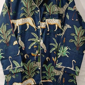 Puede incluir: Camisa de pijama azul marino con estampado de jungla. La camisa de manga larga tiene ribetes blancos y cierre de botones. El estampado incluye leopardos, cebras, loros, flamencos y palmeras.
