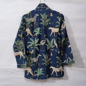 Puede incluir: Una camisa de pijama azul marino de manga larga con un estampado de animales de la jungla. El estampado presenta cebras, leopardos, p&aacute;jaros y palmeras. La camisa tiene ribetes blancos.