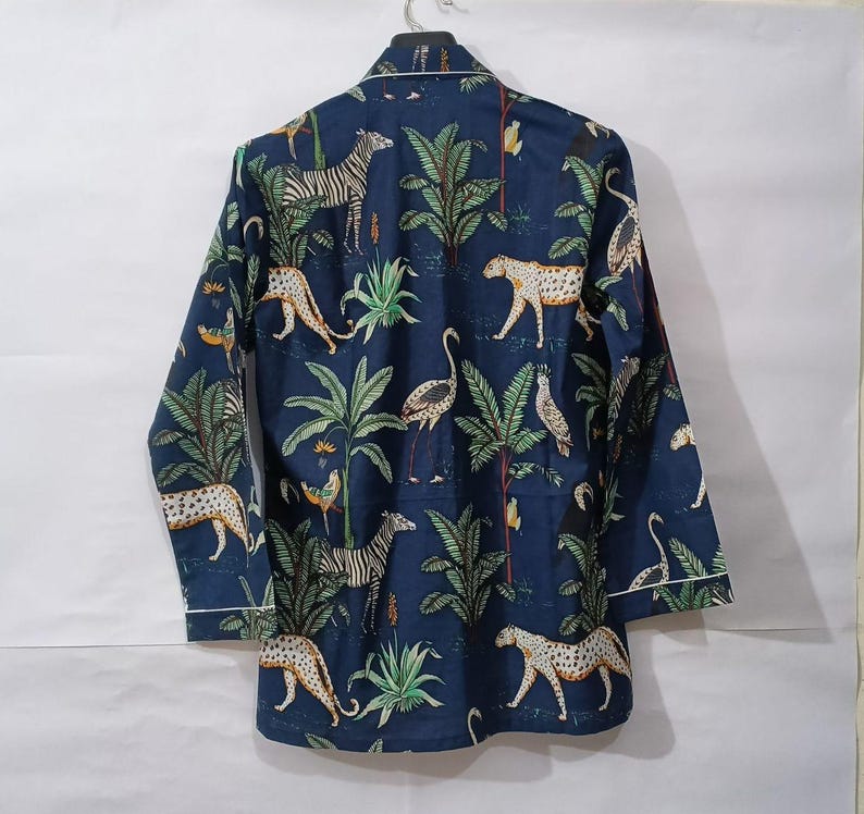 Puede incluir: Una camisa de pijama azul marino de manga larga con un estampado de animales de la jungla. El estampado presenta cebras, leopardos, p&aacute;jaros y palmeras. La camisa tiene ribetes blancos.