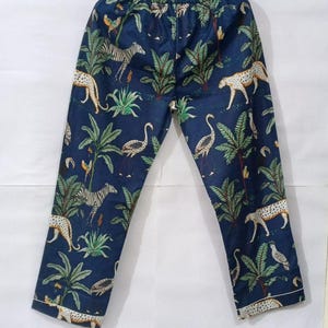 Puede incluir: Pantalones de pijama azul oscuro con estampado de animales de la jungla. Los pantalones presentan cebras, leopardos y p&aacute;jaros entre palmeras y otro follaje. Los pantalones tienen un ribete blanco en la parte inferior.