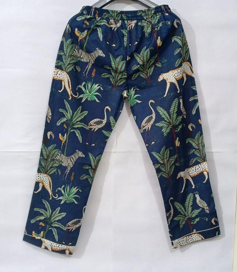 Puede incluir: Pantalones de pijama azul oscuro con estampado de animales de la jungla. Los pantalones presentan cebras, leopardos y p&aacute;jaros entre palmeras y otro follaje. Los pantalones tienen un ribete blanco en la parte inferior.