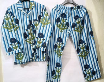 May include: A two-piece pajama set consisting of a long-sleeved button-down shirt with a collar and matching pants with an elastic waistband. The set features a vertical blue and white striped pattern with a dark blue floral print and green stems.