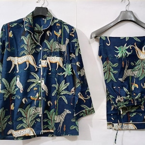Puede incluir: Conjunto de pijama azul marino con estampado de animales de la jungla. El conjunto incluye una camisa con botones y pantalones a juego, ambos con un estampado de leopardos, cebras y follaje tropical. Ribete blanco.