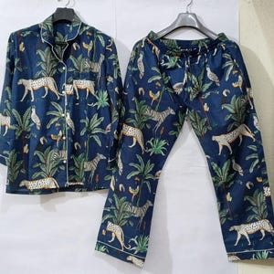 Puede incluir: Conjunto de pijama azul marino con estampado de animales de la jungla. El conjunto incluye una camisa con botones y pantalones a juego. El estampado presenta cebras, leopardos, p&aacute;jaros y follaje tropical.