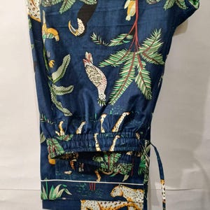 Puede incluir: Pantalones de pijama azul oscuro con estampado de tem&aacute;tica selv&aacute;tica. El dise&ntilde;o presenta cebras, leopardos, tucanes y exuberante follaje verde. Los pantalones tienen cintura con cord&oacute;n y ribete blanco.