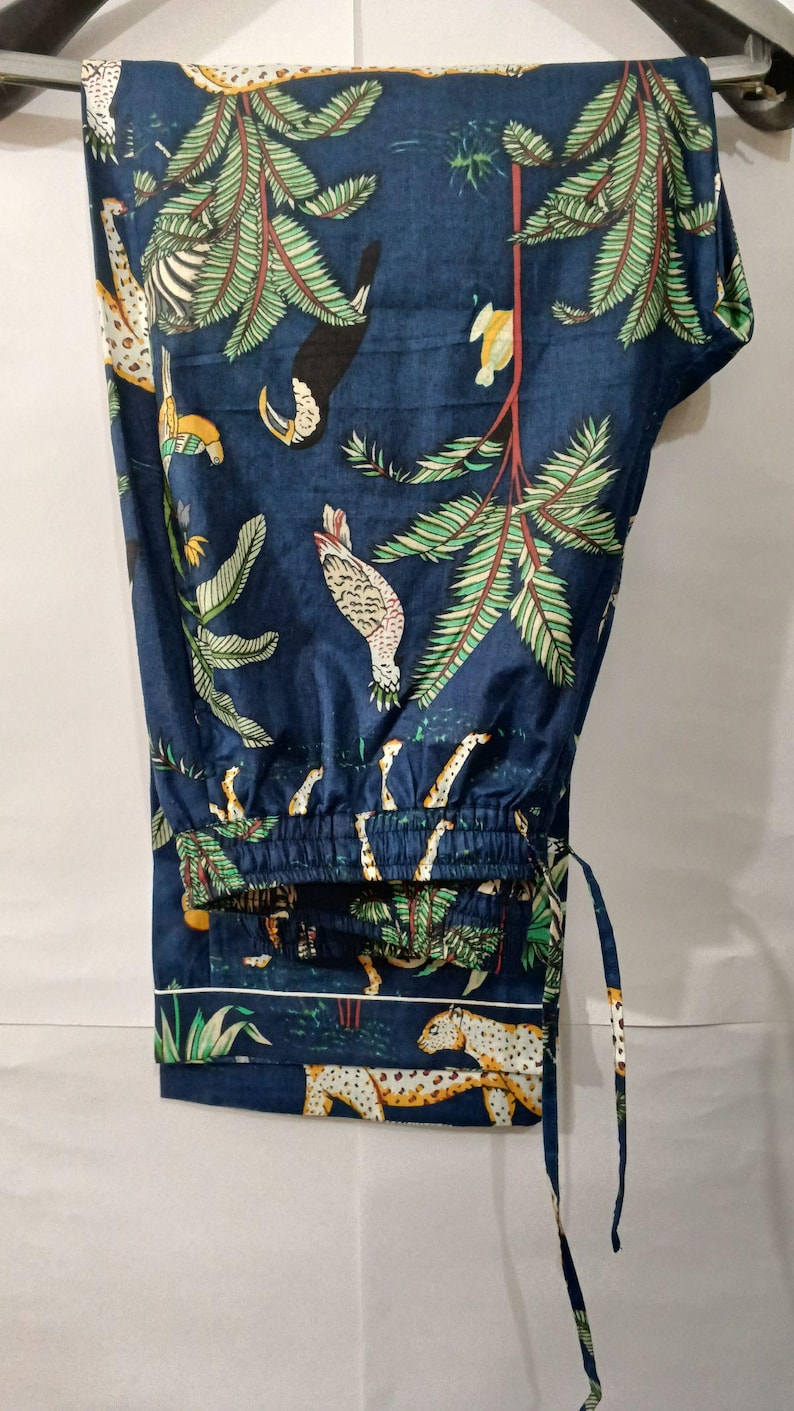 Puede incluir: Pantalones de pijama azul oscuro con estampado de tem&aacute;tica selv&aacute;tica. El dise&ntilde;o presenta cebras, leopardos, tucanes y exuberante follaje verde. Los pantalones tienen cintura con cord&oacute;n y ribete blanco.