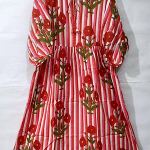 以下が含まれることがあります： 赤、ピンク、白のストライプ柄のロングドレス。花柄が施されています。ドレスは七分袖で、首元にはリボンが付いています。花柄は赤い花と緑の葉で構成されています。