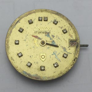 May include: A vintage Onyx watch face with a gold-toned finish. The face features diamond-like markers, the text "ONYX" and "17 JEWELS", and a date display showing "22". The watch hands are black.