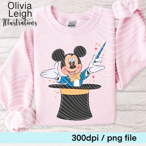 May include: Pale pink sweatshirt with a cartoon Mickey Mouse magician design. Mickey is emerging from a black top hat with a yellow band, holding a blue wand. The text reads "Olivia Leigh Illustrations" and "300dpi / png file".