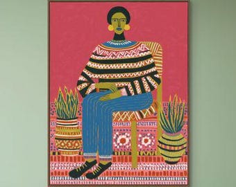 May include: A framed art print featuring a seated figure in a striped sweater and blue pants. The artwork is set against a red background, with potted plants on either side. The room has a sofa with pillows and a woven ottoman.