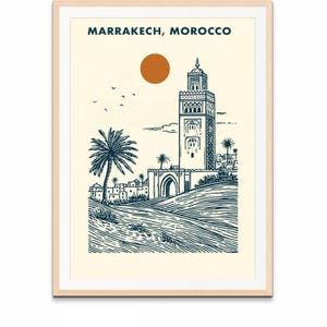 May include: Framed art print featuring a navy blue and cream illustration of Marrakech, Morocco. The artwork depicts a tall minaret, palm trees, and a rising sun. The text "MARRAKECH, MOROCCO" is printed at the top.