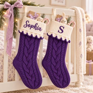 Puede incluir: Dos calcetines navideños de punto trenzado morado con puños acanalados blancos y bordes festoneados. Un calcetín está bordado con el nombre Sophia y el otro con la letra S. Cada uno contiene una pequeña caja de regalo, un peluche y un bastón de caramelo.