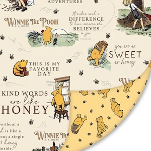 May include: A cream-colored fabric featuring Winnie the Pooh illustrations, bees, and quotes like 'Kind words are like honey'. The reverse side is yellow with a repeating pattern of Pooh bears and bees. A 12-inch ruler is visible at the bottom.