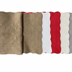 May include: Set of five quilted table runners in various colors, including beige, white, red, and gray. Each runner features a scalloped edge and a quilted design.