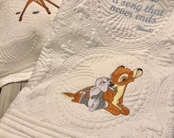 May include: White quilted baby blanket with embroidered images of Bambi and Thumper. One blanket features the quote "Love is a song that never ends" from the movie Bambi. The blankets have a detailed, quilted pattern.